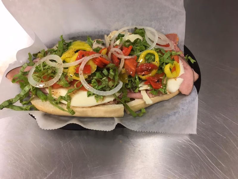 Deli sub topped with lettuce, tomato, onions and peppers