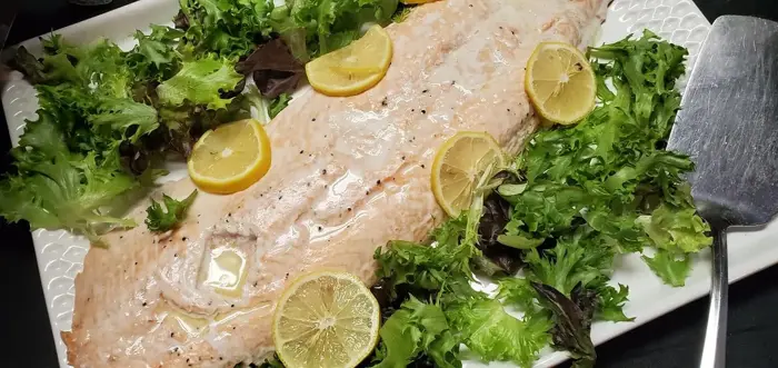 Baked salmon fillet with lemon slices on mixed greens